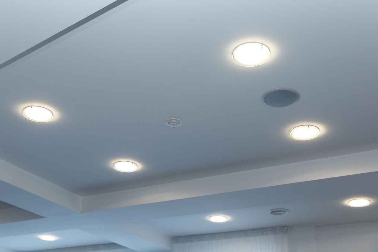 Modern layered ceiling with embedded lights and stretched ceiling inlay, lights on.