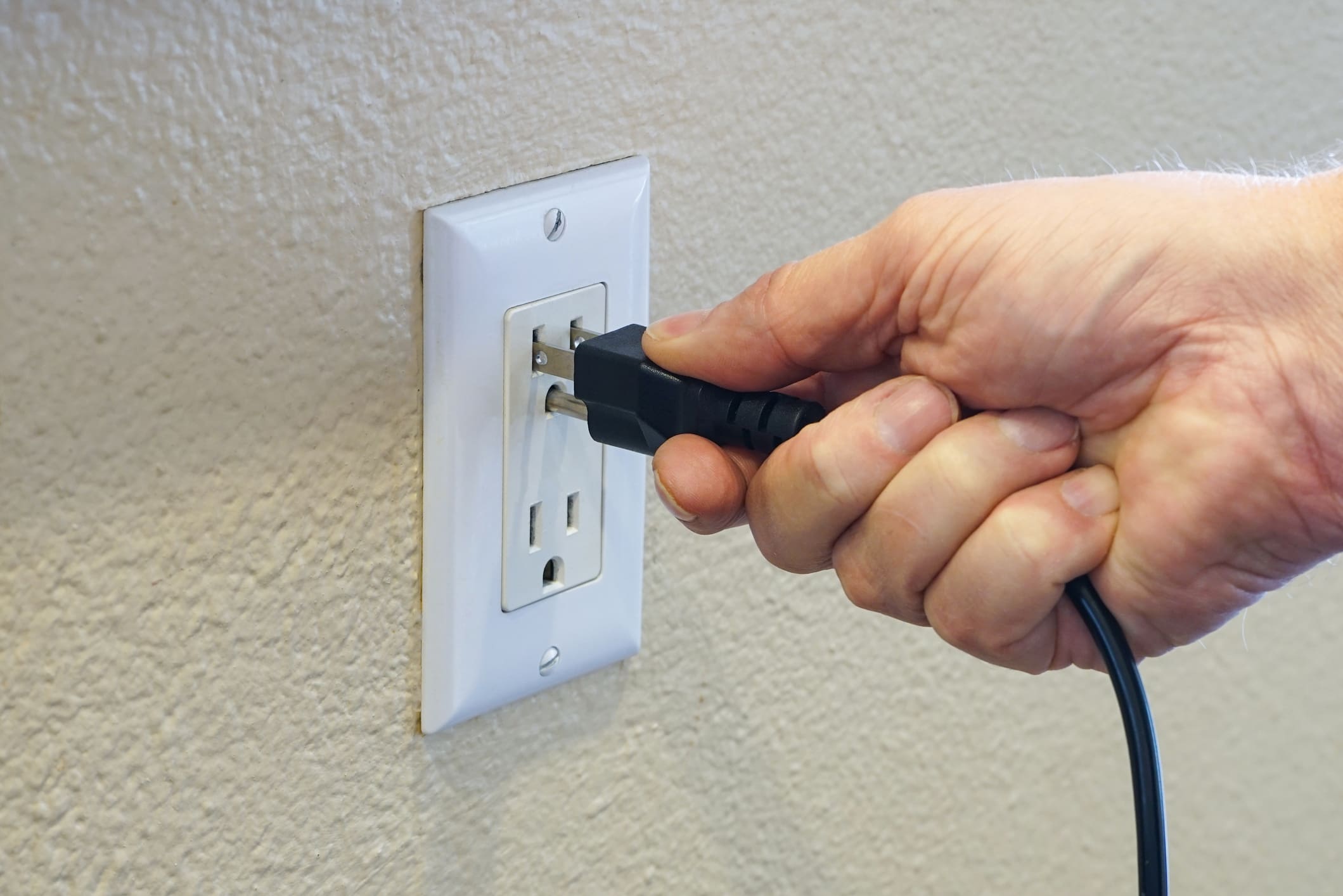 Hand Plugging Cord Into Outlet